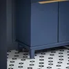 A close-up view of a blue bathroom cabinet with a wooden handle, resting on a patterned tile floor. Produktbild-Vorschau