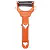 An orange vegetable peeler with a heart-shaped cutout on the handle, shown against a white background. Voir les images du produit