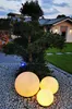 Outdoor garden scene at dusk with illuminated spherical lights in the foreground and a modern house in the background. Produktbild-Vorschau