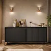 A modern living room setting with a black sideboard, decorative items, and wall sconces. Produktbild-Vorschau