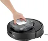 A hand is shown inserting a water tank into a black robot vacuum cleaner. Produktbild-Vorschau