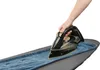 A hand is shown ironing a piece of blue denim fabric on a grey ironing board. Produktbild-Vorschau