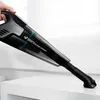 A hand holding a black and gray handheld vacuum cleaner with a transparent dustbin, positioned over a white surface. Podgląd zdjęcia produktu