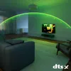 A living room with a sofa, armchair, and television, with green light effects emanating from the TV. Náhled obrázku produktu