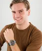 A man wearing a brown t-shirt and a watch on his left wrist, smiling at the camera. Podgląd zdjęcia produktu