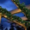 A Christmas garland with lights draped over a wooden pergola at dusk. Anteprima dell’immagine prodotto