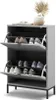 A gray shoe cabinet with two flip-down drawers, filled with shoes, is shown against a white background. A decorative plant in a vase sits on top of the cabinet. Podgląd zdjęcia produktu