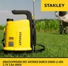 A yellow battery-powered sprayer is shown in a grassy field with a person in the background. Podgląd zdjęcia produktu
