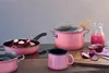 A collection of pink cookware and kitchen items arranged on a wooden surface with a gray background. Anteprima dell’immagine prodotto