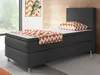 A single bed with a dark gray upholstered base and headboard, featuring a white mattress, a pillow with an orange and white zigzag pattern, and a matching throw blanket draped over the mattress. Produktbild-Vorschau