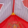 A close-up view of the interior structure of a children's play tent, showing red support poles connected by a yellow joint, with red fabric featuring a fire department emblem visible at the bottom. Produktbild-Vorschau