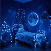 A child's bedroom decorated with a space theme, featuring a bed, tent, and celestial decorations illuminated by blue fairy lights. Produktbild-Vorschau