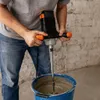 A person is using a mortar mixer to mix material in a blue bucket. Anteprima dell’immagine prodotto