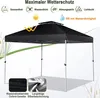 A black pop-up gazebo with water droplets on the fabric, set against a background of reeds and grass. Produktbild-Vorschau