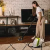 A woman is using a steam cleaner on a wooden floor in a living room. Anteprima dell’immagine prodotto