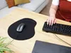A person's hands are shown typing on a keyboard and using a mouse on a wooden desk. Anteprima dell’immagine prodotto