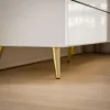 Close-up of the legs and bottom of a white dresser with gold legs. Produktbild-Vorschau