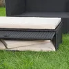 A close-up view of outdoor furniture, specifically a black rattan sofa or bench with beige cushions, placed on green grass. Podgląd zdjęcia produktu