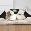 A golden retriever puppy lies on a large, beige and black dog bed. Voir les images du produit
