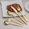 A set of gold-colored cutlery is arranged on a white plate with a steak, next to a white plate. Anteprima dell’immagine prodotto