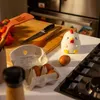 A kitchen counter with cooking ingredients and utensils, featuring a chicken-shaped stress toy. Voir les images du produit
