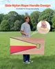 A young man stands in a grassy field holding a cornhole board. The board has a red and yellow design. There is an inset image showing a hand holding a rope handle. Produktbild-Vorschau
