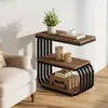 A narrow, three-tiered side table with a wood-look top and black metal frame, placed next to a beige armchair in a room with wooden flooring and a white wall. Produktbild-Vorschau