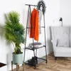 A clothing rack with clothes and accessories, next to a plant and a chair. Náhľad obrázku produktu