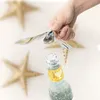 A hand is using a bird-shaped bottle opener to open a bottle of soda, with starfish in the background. Podgląd zdjęcia produktu