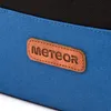 A close-up of a blue and black bag with a brown leather logo. Náhled obrázku produktu