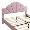 A close-up view of a pink upholstered bed frame with a fan-shaped headboard and wooden slats for the mattress. Produktbild-Vorschau