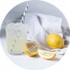 A glass of lemonade with ice and a straw, next to lemons and a white cloth. Produktbild-Vorschau