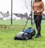 A woman is mowing a lawn with a cordless lawnmower. Podgląd zdjęcia produktu