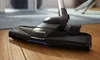 Close-up of a vacuum cleaner head on a wooden floor and a rug. Produktbild-Vorschau