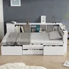 A white multifunctional single bed with storage drawers and a bookshelf headboard, set against a dark gray wall with a subtle speckled pattern. Produktbild-Vorschau