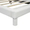 Close-up view of the corner and leg of a white upholstered bed frame, showing the wooden slats of the bed base. Produktbild-Vorschau
