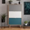 A modern shoe cabinet with three colored drawers is shown in a room with plants and artwork. Produktbild-Vorschau