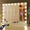 A vanity mirror with lights and makeup brushes on a dresser in front of a wardrobe. Produktbild-Vorschau