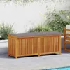 An outdoor storage bench with a cushion sits on a patio next to a swimming pool. Náhled obrázku produktu