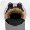 A close-up view of a baby stroller footmuff with a hood featuring bear ears and faux fur trim. A diagram of a zipper is shown in the upper left corner. Náhled obrázku produktu