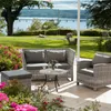 An outdoor patio setting with wicker furniture, flowers, and a view of a lake and bridge. Produktbild-Vorschau