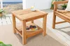A wooden side table with a shelf, placed on a rug on a deck with a view of the ocean. Produktbild-Vorschau