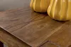 A close-up view of a wooden table surface with two decorative yellow vases on it. Produktbild-Vorschau