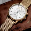 A close-up shot of a gold Tommy Hilfiger watch with a white face, resting on a brown textured surface. Voir les images du produit