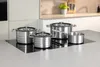 A set of stainless steel pots and pans on a modern induction stovetop. Produktbild-Vorschau