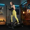 A woman is exercising on an elliptical machine in a home gym. Produktbild-Vorschau