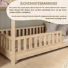 A wooden bed with a safety barrier, with text overlay describing its features. Produktbild-Vorschau