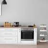 A kitchen scene with a white trolley on the right, a stove and cabinets on the left. Produktbild-Vorschau