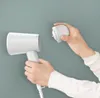 A person is holding a white hairdryer and a white attachment. Produktbild-Vorschau