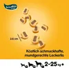 A collection of dog treats scattered on a yellow background, with a size indicator and descriptive text. Náhľad obrázku produktu